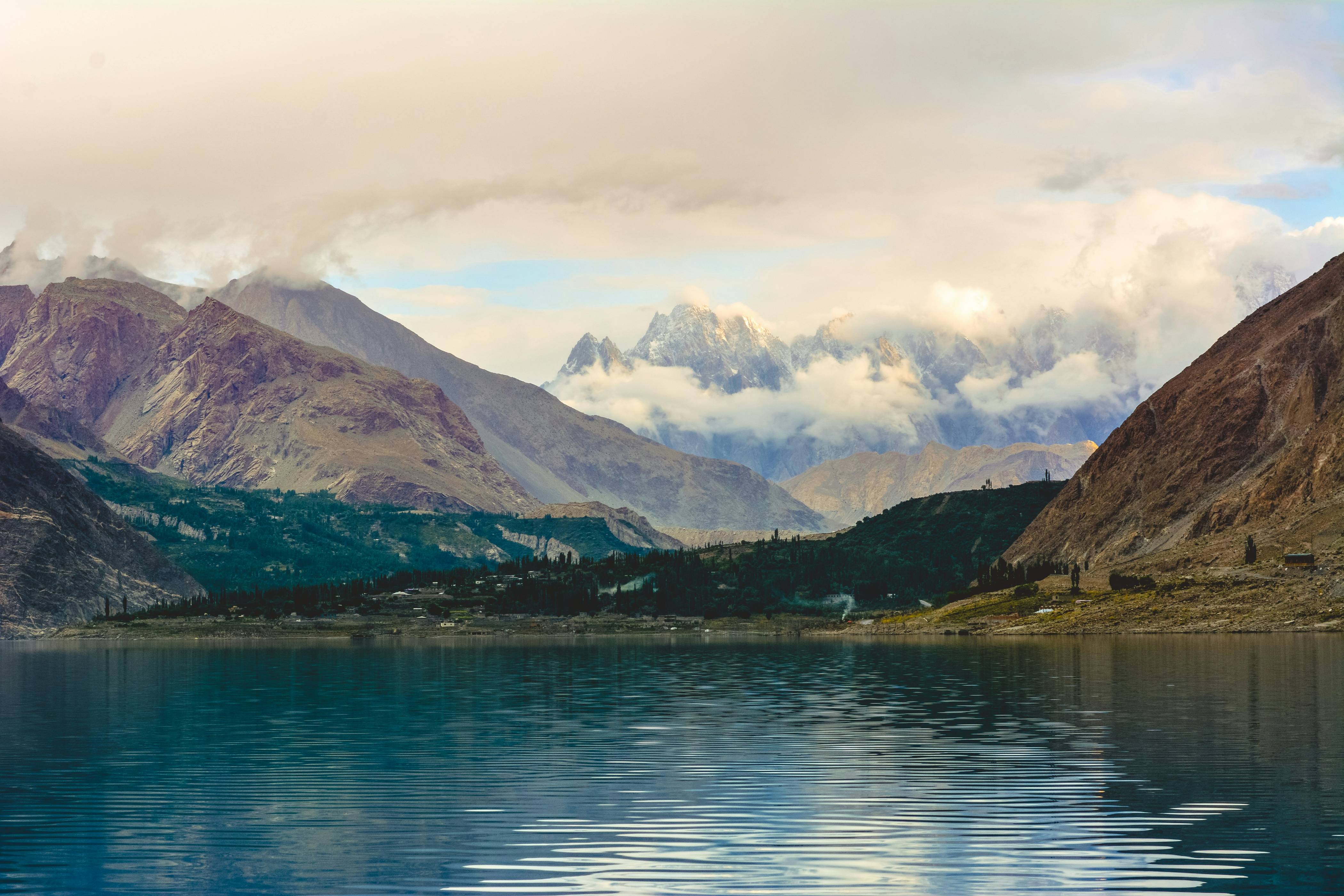 green and brown mountains beside body of water under white clouds during daytime