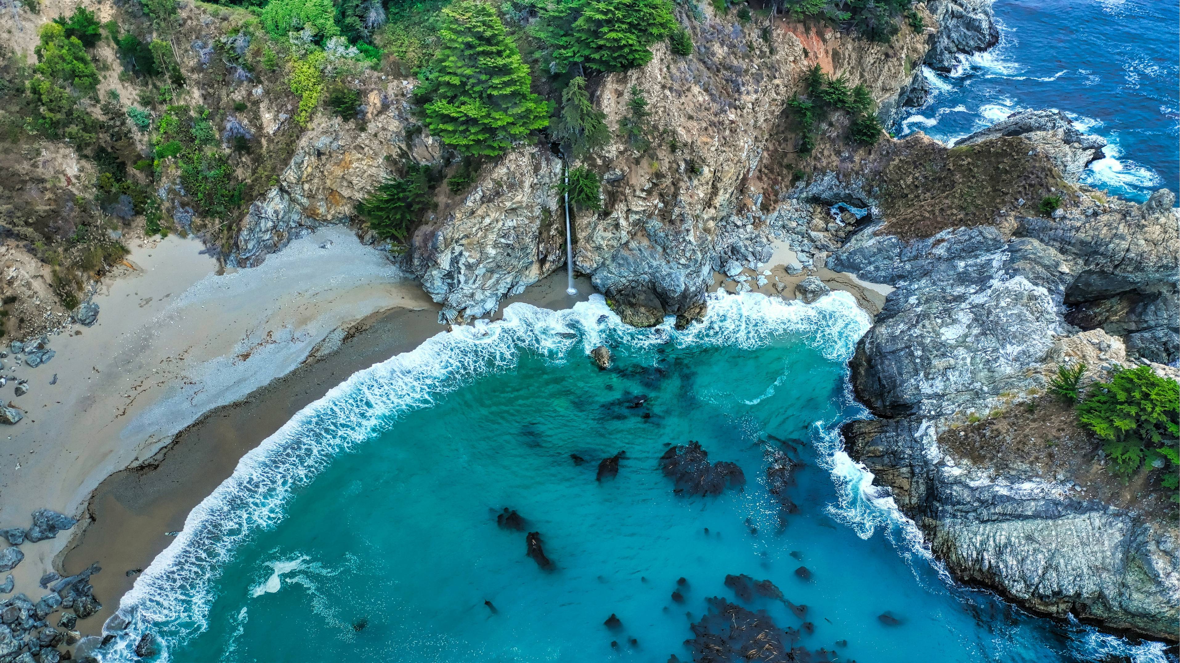 aerial photography of waves splashing by the seashore