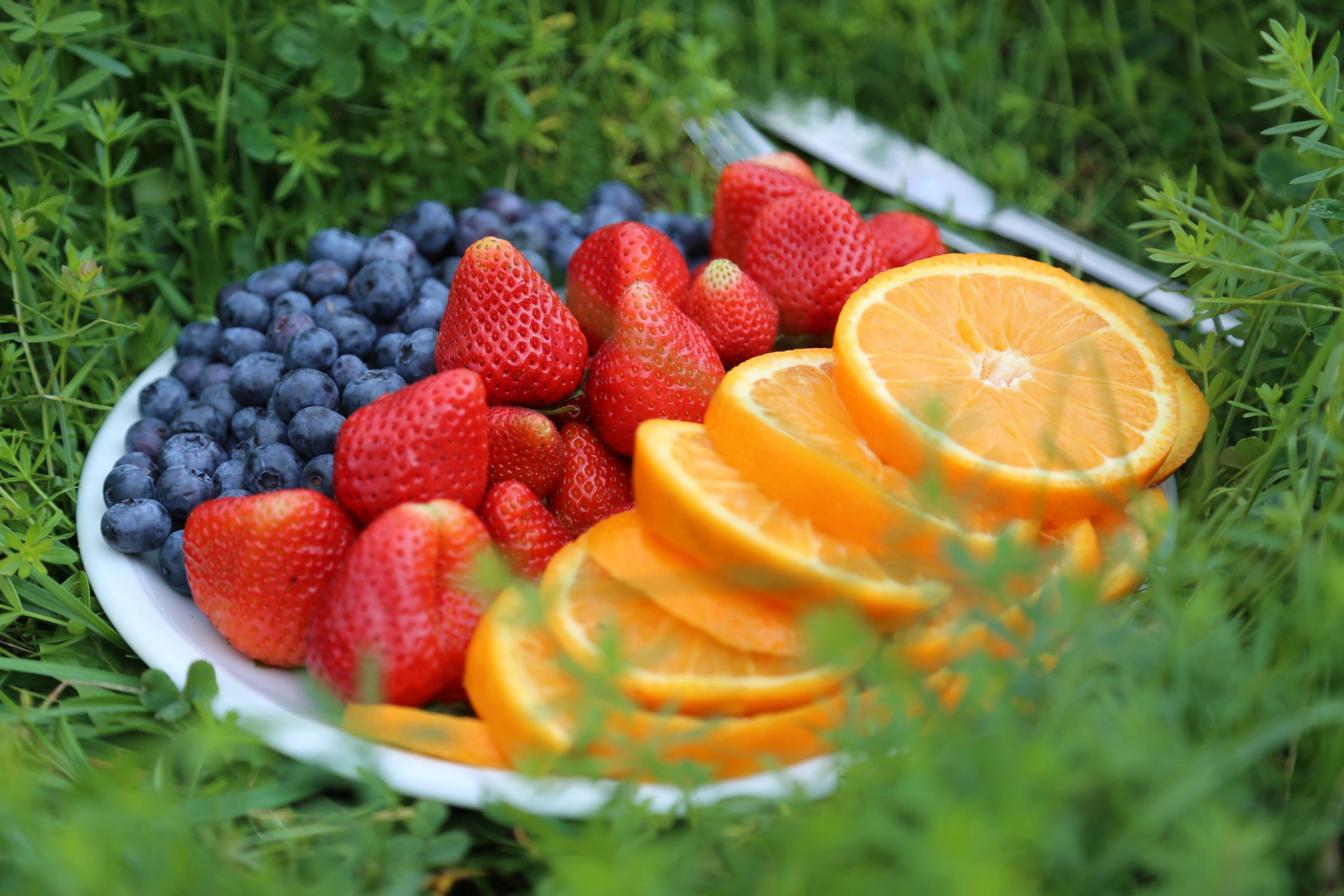 a plate of fruit with oranges, strawberries, and blueberries