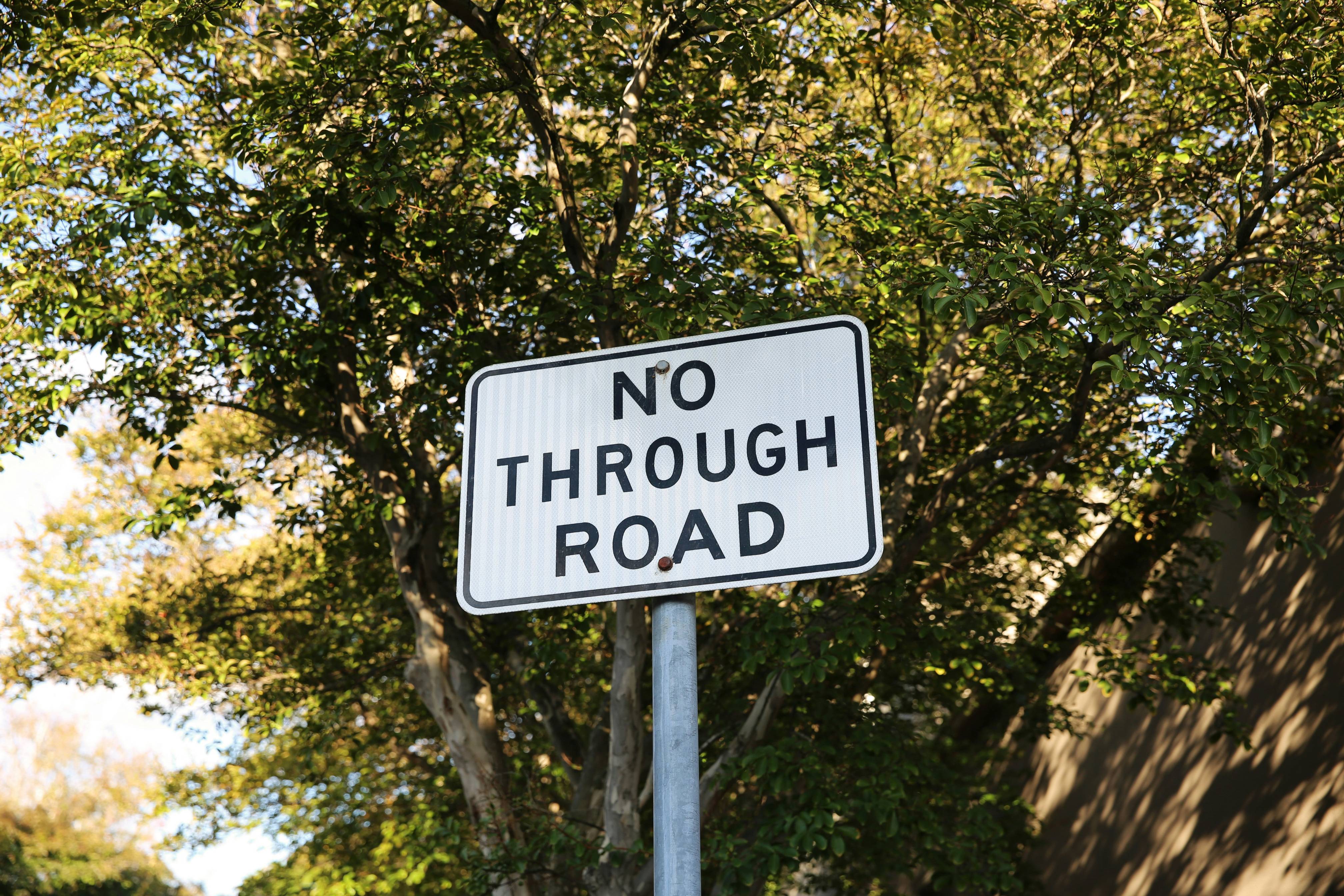 No through road sign with leafy backdrop.